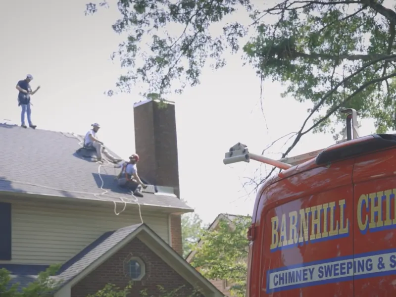 Barnhill Chimney crew working on a rooftop with the branded truck below
